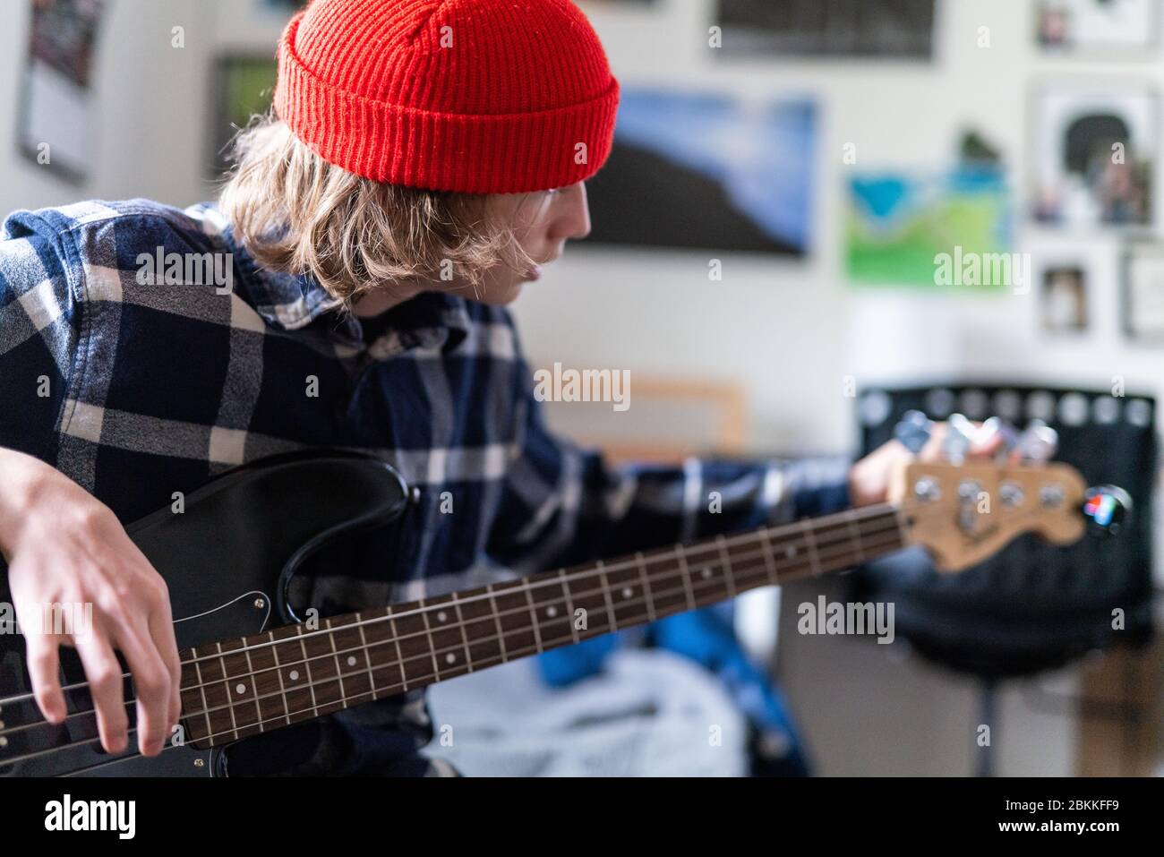 Teenager turning tuning keys on head of bass guitar white tuning Stock Photo