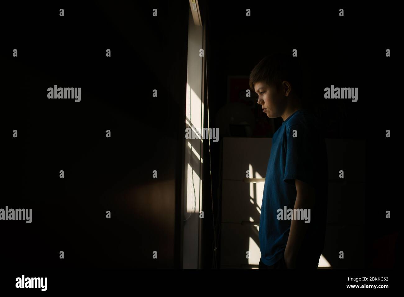 Young teen boy looking out the window during isolation Stock Photo - Alamy