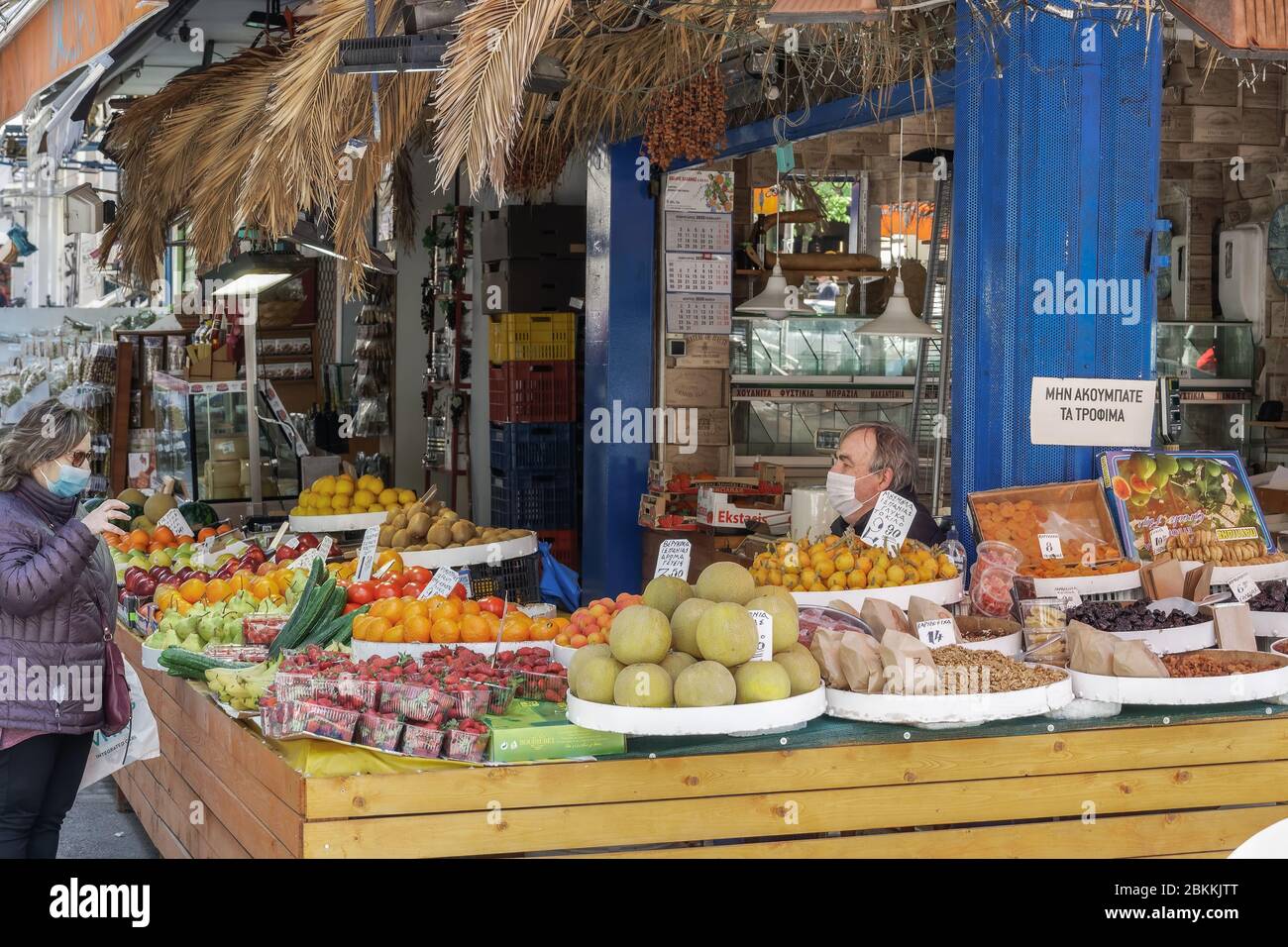 Greengrocer shop with owner & customer wearing protective masks. Greek