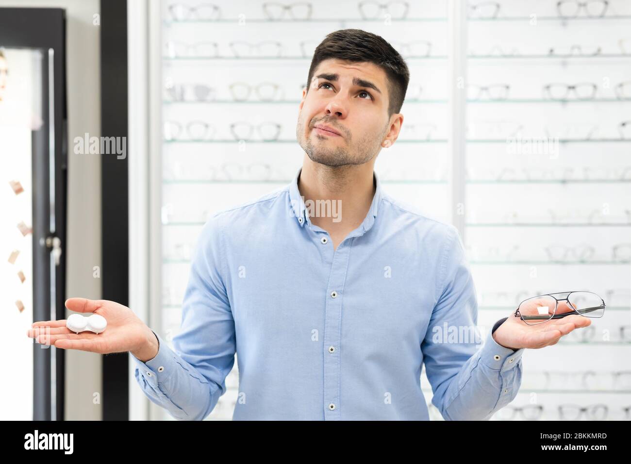 Pensive man choosing between eyeglasses and contacts Stock Photo