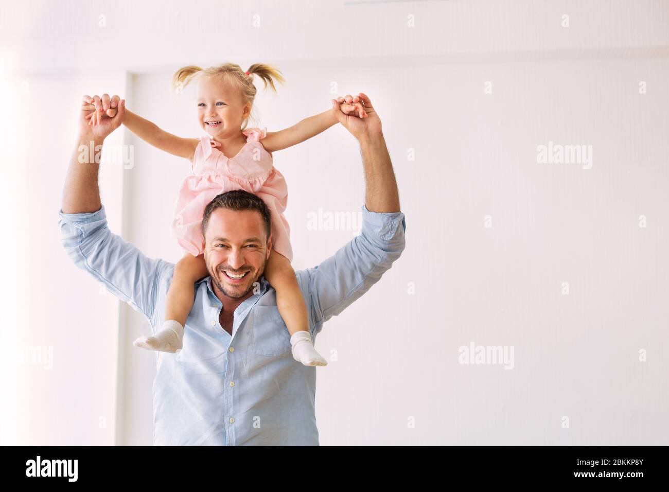 Millennial father riding his cute daughter on shoulders Stock Photo
