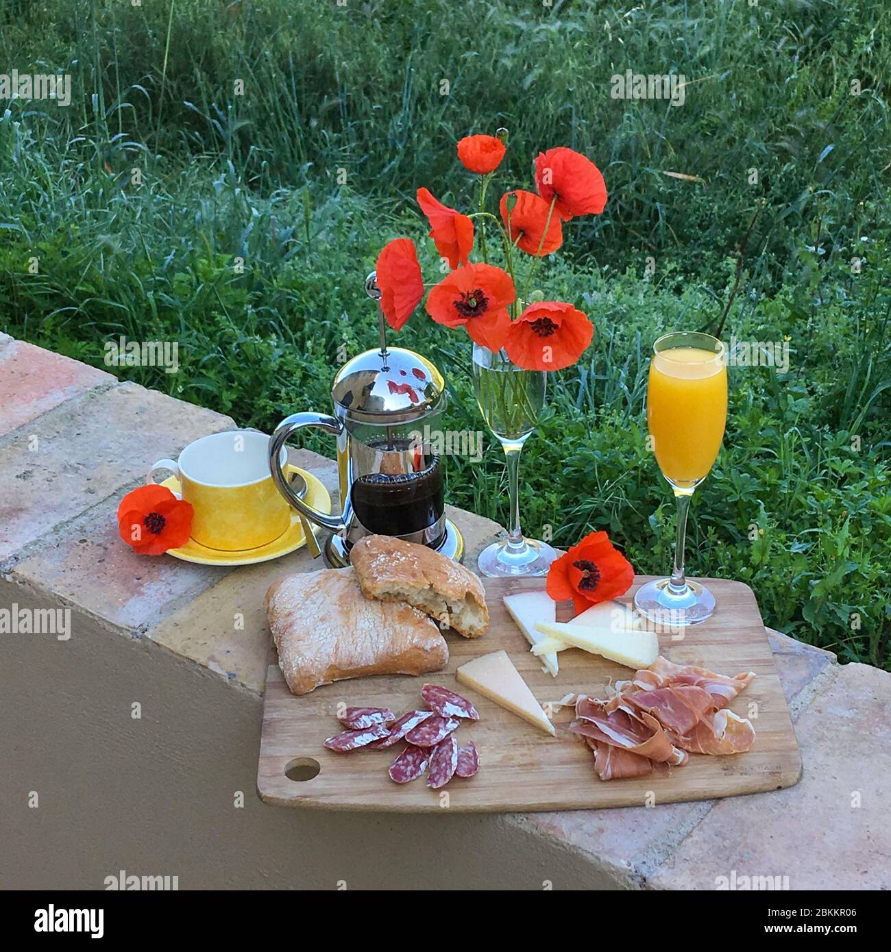 breakfast with Jamon, juice, coffee, cheese, bread and poppy flowers Stock Photo