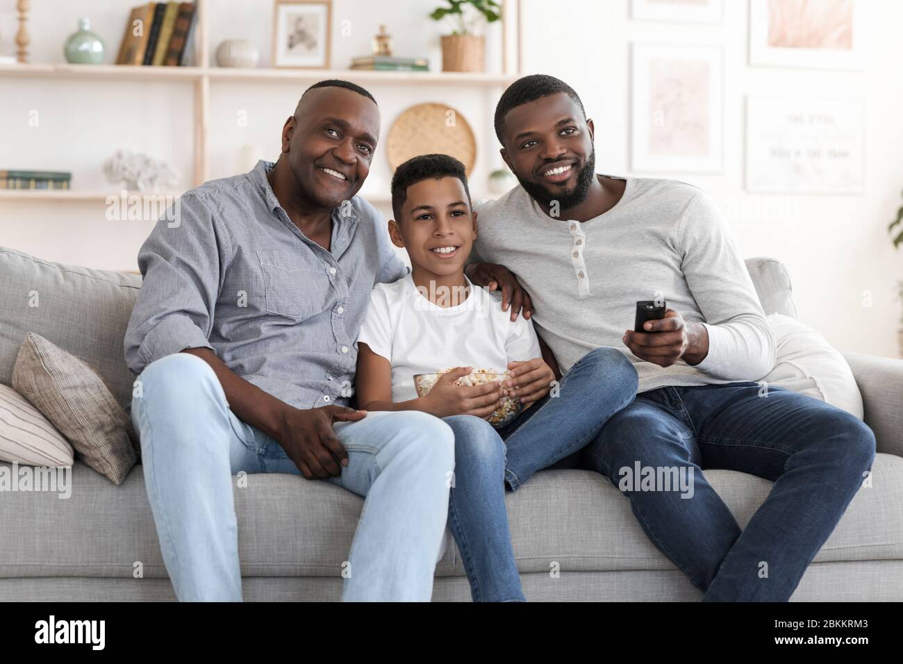 Happy African Grandfather, Father And Son Watching TV At Home Together Stock Photo