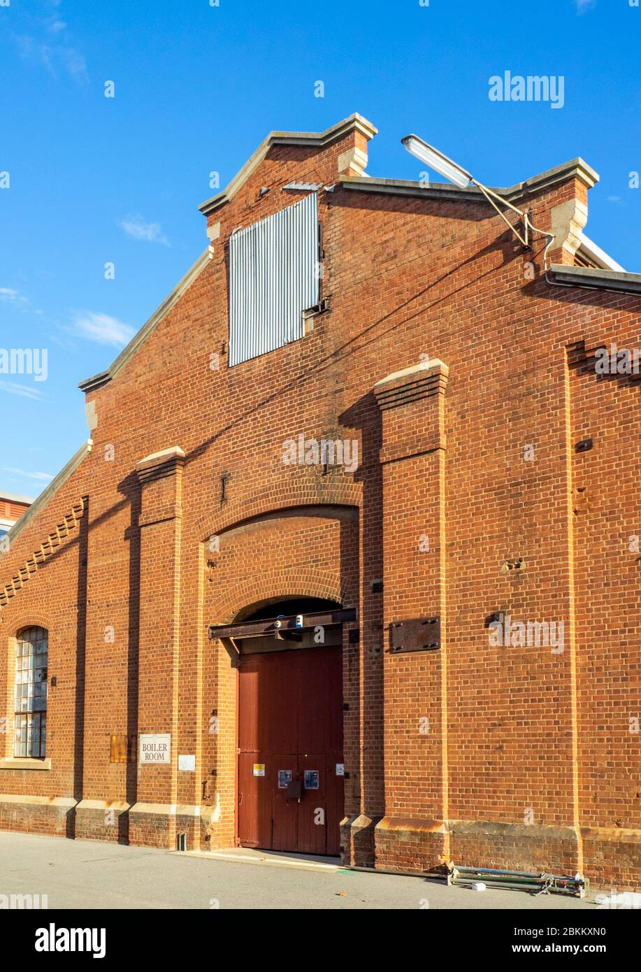 A large red brick building with a green roof photo – Free