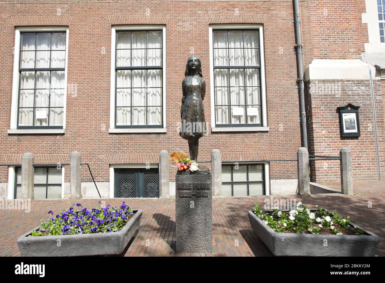 Flowers laid at the Anne Frank (1929-1945) statue near Anne Frank house on empty street during the Remembrance Day to celebrate 75 Years of the War vi Stock Photo