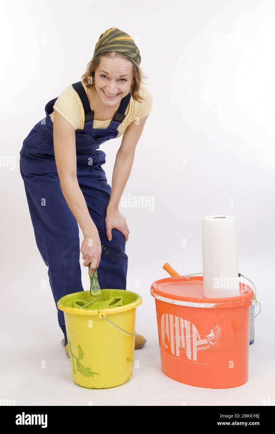 Junge Frau renoviert die Wohnung und ruehrt einen Eimer mit Farbe an, MR: Yes Stock Photo