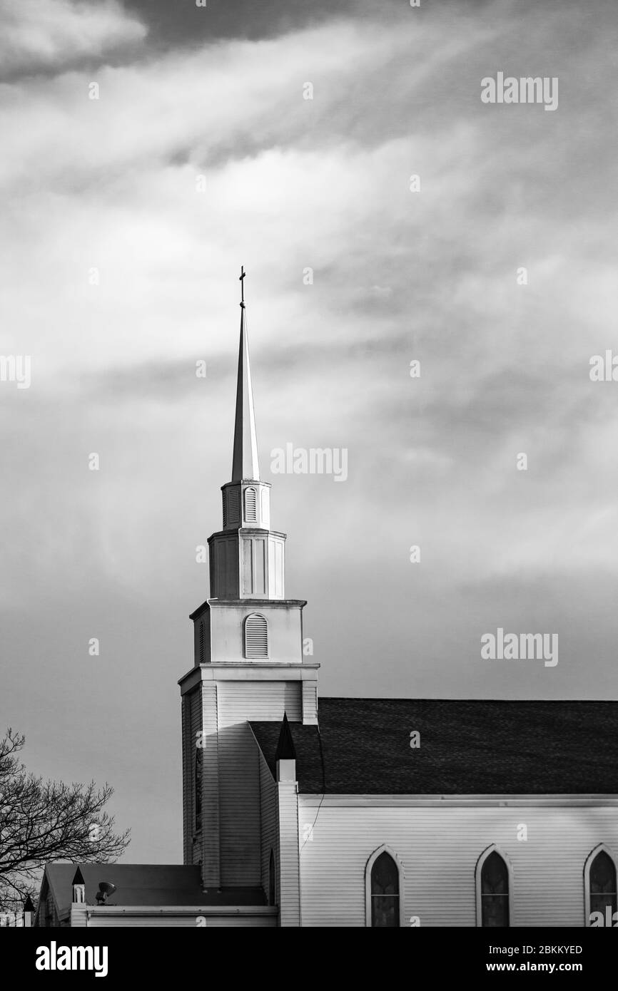 Cross high on top of a 150 year old Wisconsin church steeple in the late afternoon, black and white Stock Photo