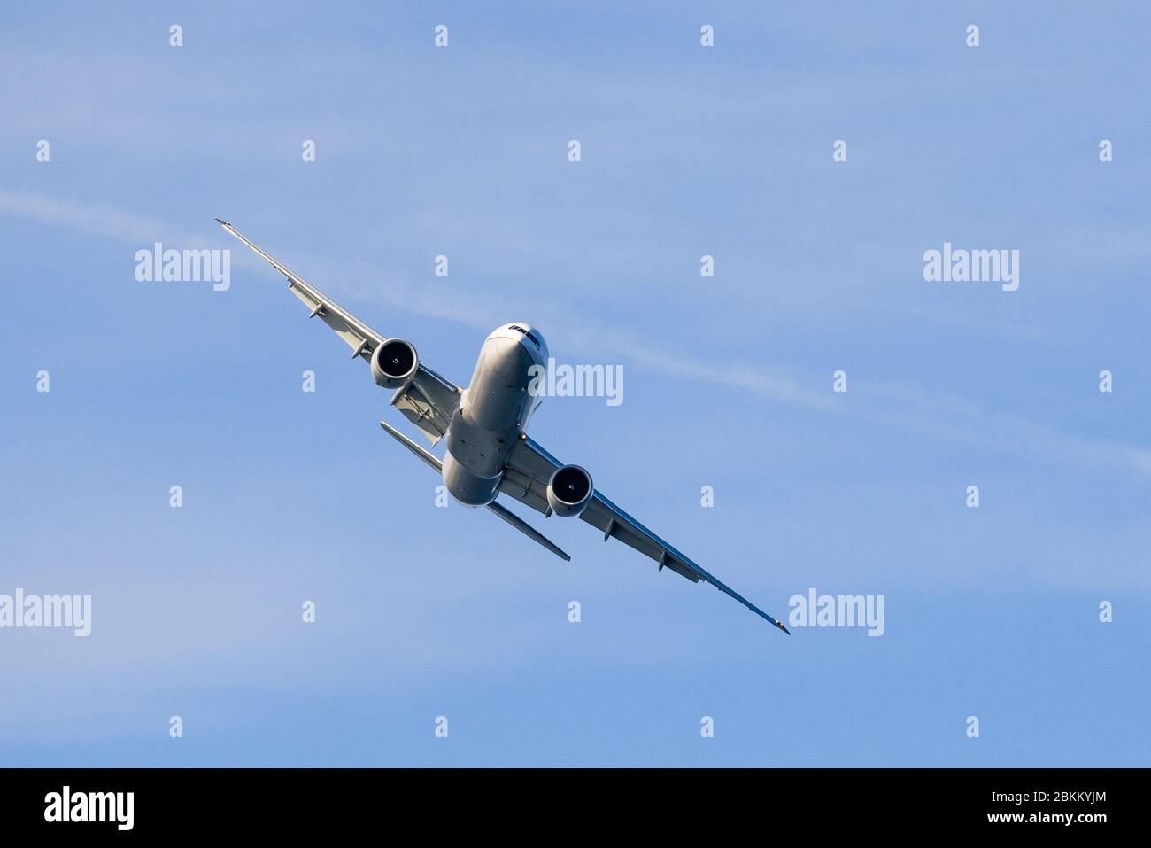 Large commercial airplane making a turn; blue sky background Stock Photo