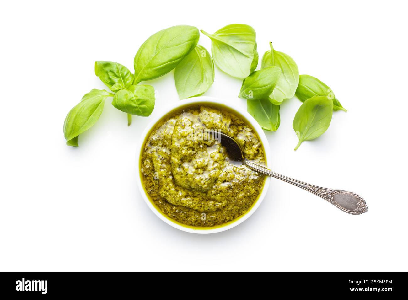 Green basil pesto dip sauce and basil leaves isolated on white
