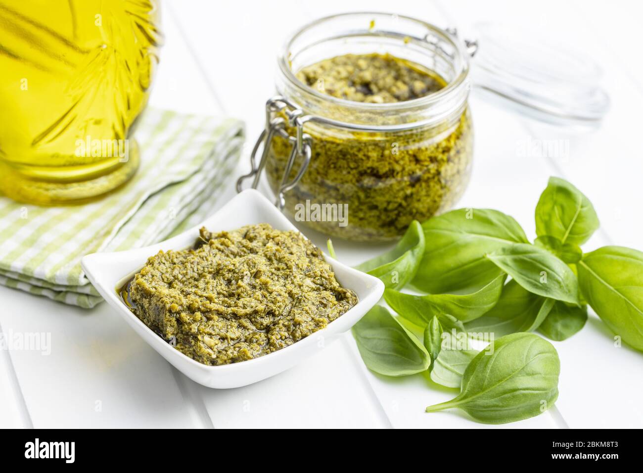 Green basil pesto dip sauce and basil leaves on white table Stock Photo