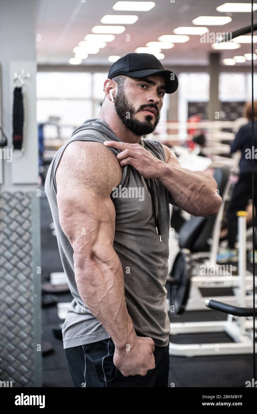 strong young bearded man showing big triceps muscle during posing in sport gym Stock Photo
