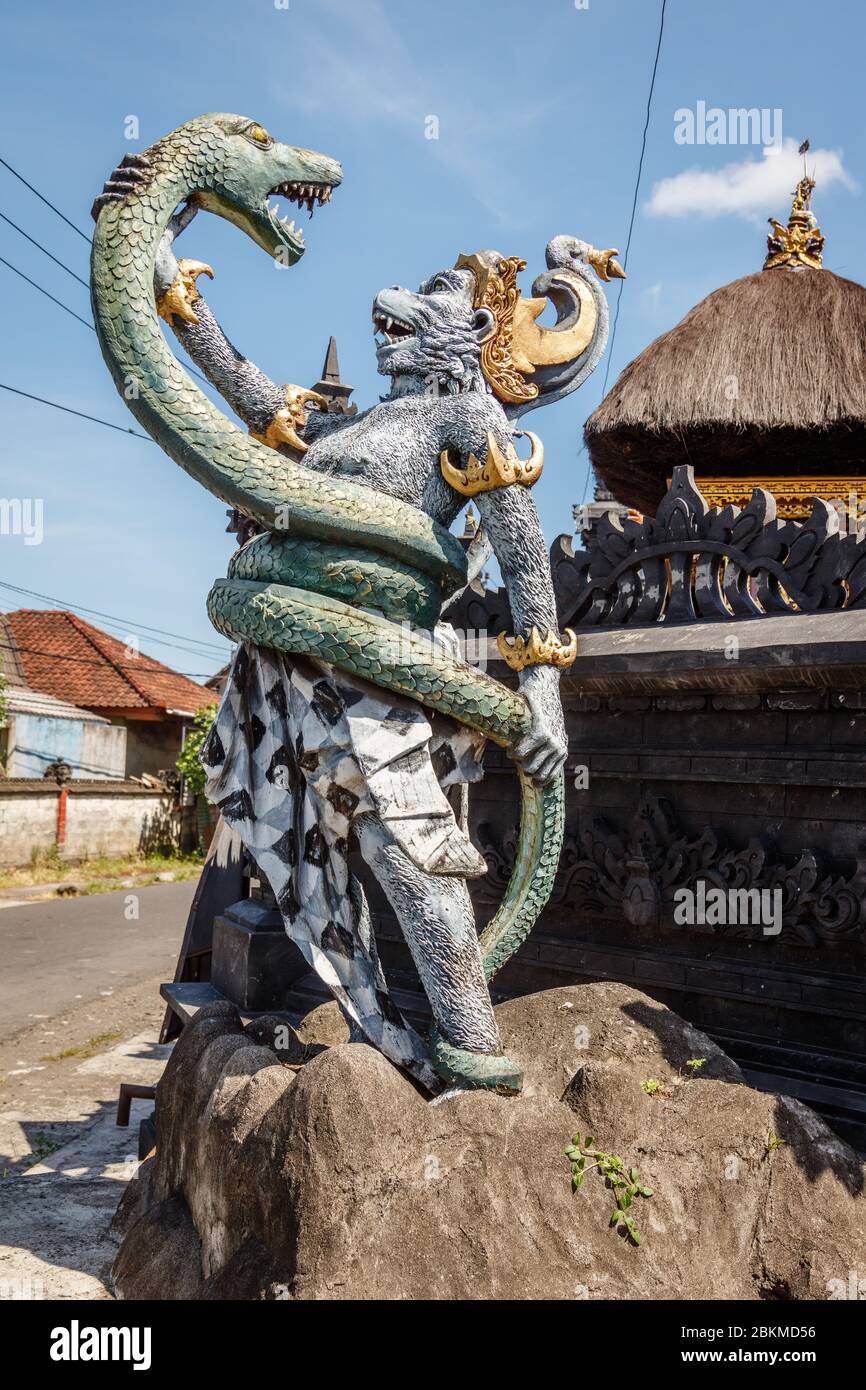 Statue of Hanuman, Hindu god and divine monkey (vanara) companion of the god Rama, fighting naga (snake). Bali, Indonesia. Vertical image. Stock Photo