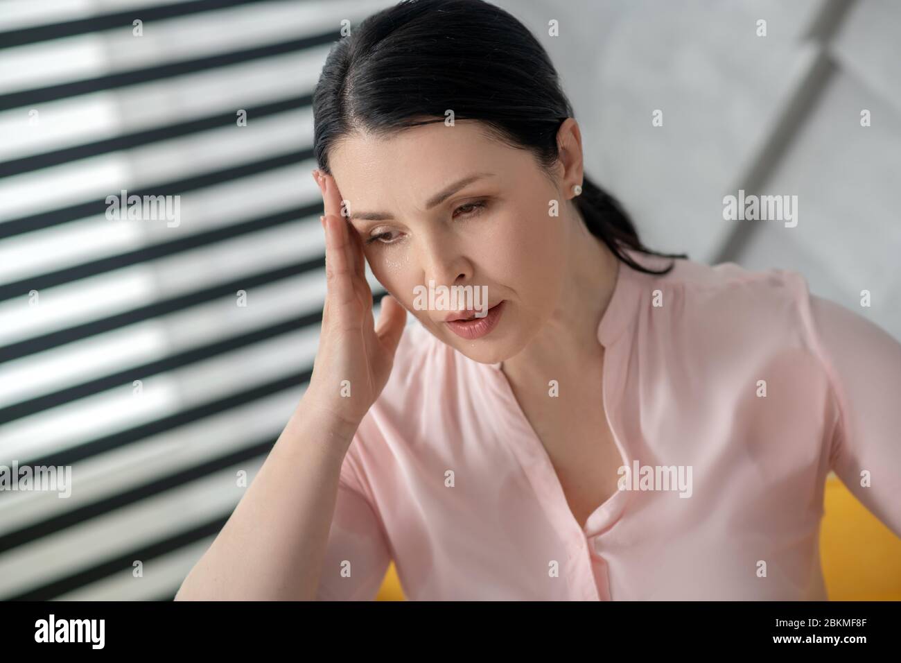 Beautiful sad adult woman holding hand near the head. Stock Photo