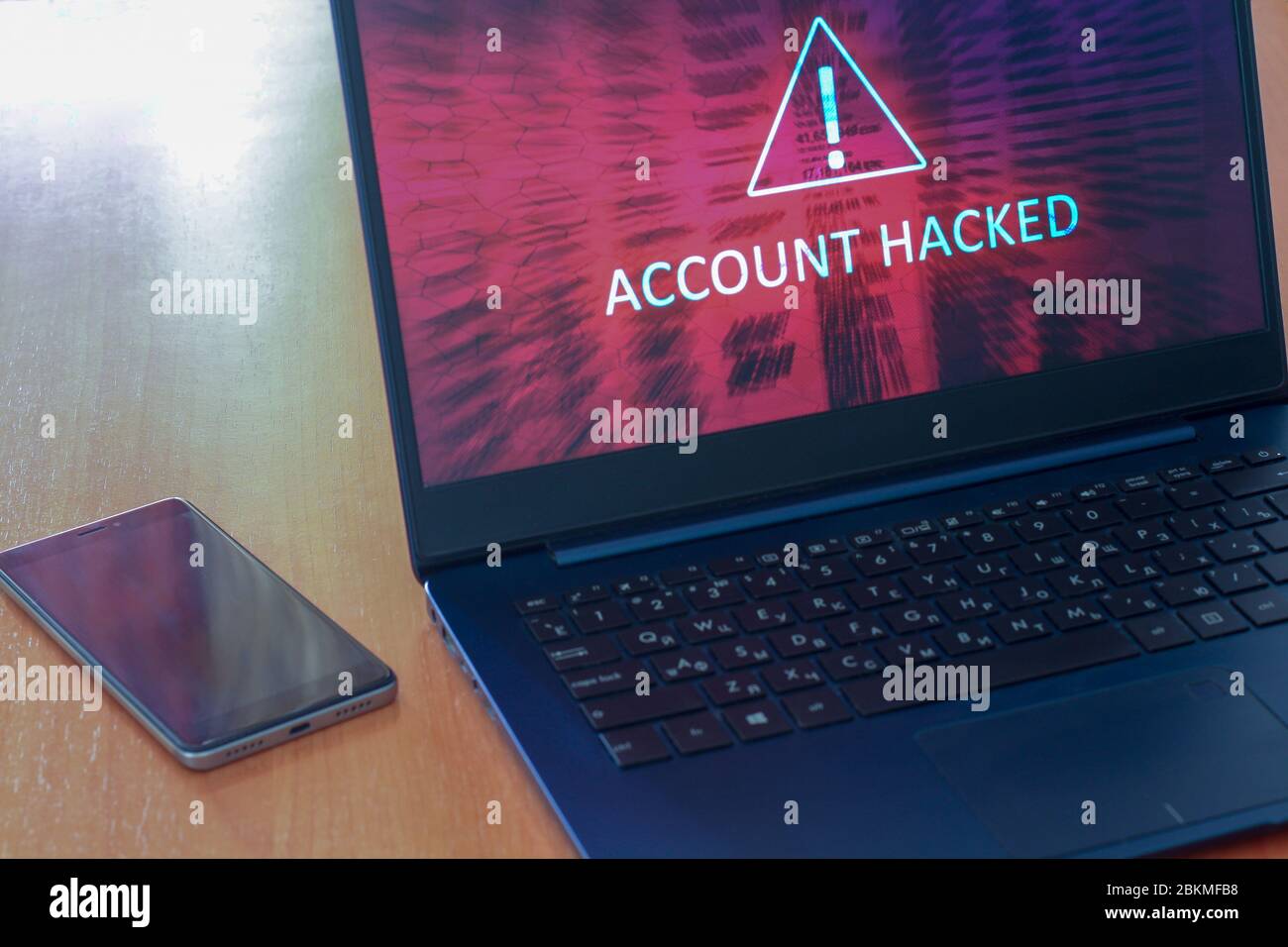 Hacked account concept on laptop screen and cellphone on a table with a ...