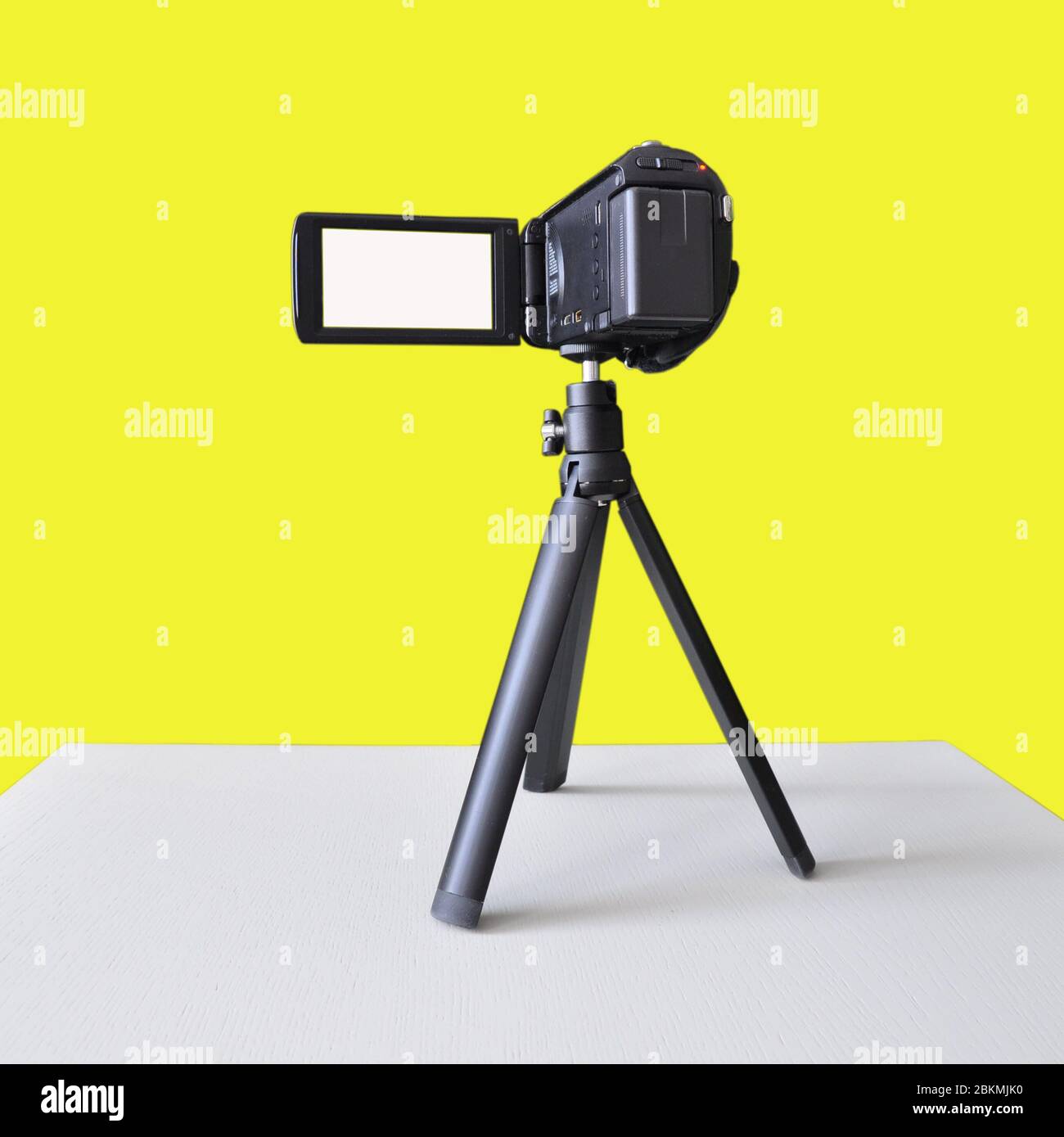 Digital video camera on a tripod isolated on a yellow. Blank for designers Stock Photo
