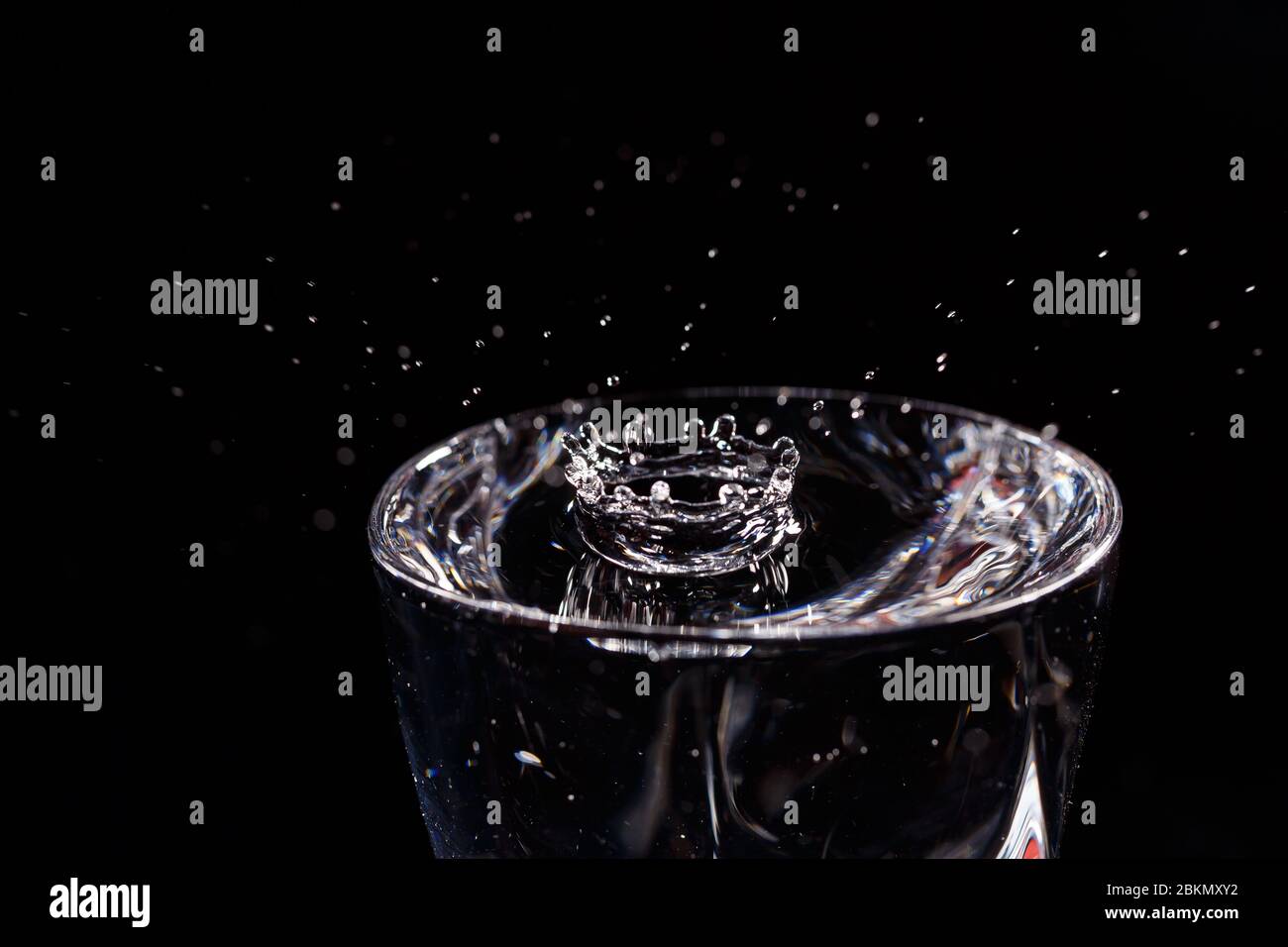 Black background is a glass in which a drop of water falls. Splashing ...