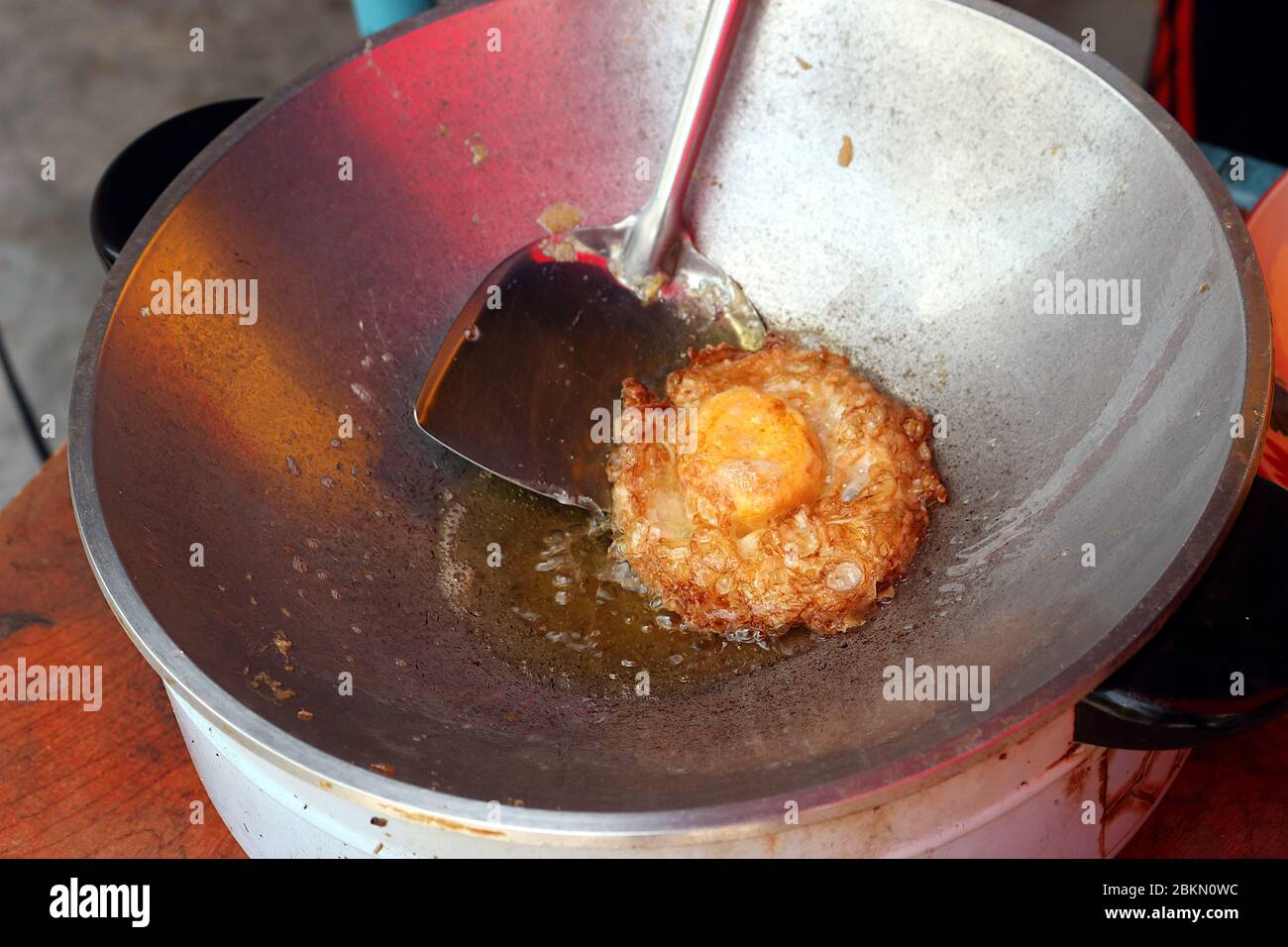 Fried eggs that are fried in an electric frying pan until crispy. There was a spatula scooping the fried egg. Stock Photo