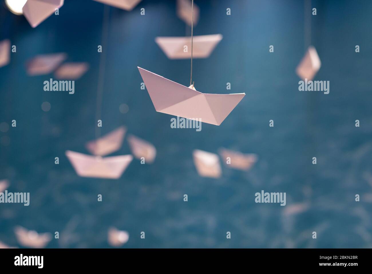 Lots of paper folded origami boats hanging in the air creating the feeling of going on a adventure and exploring the world. Decorative designs, idylli Stock Photo