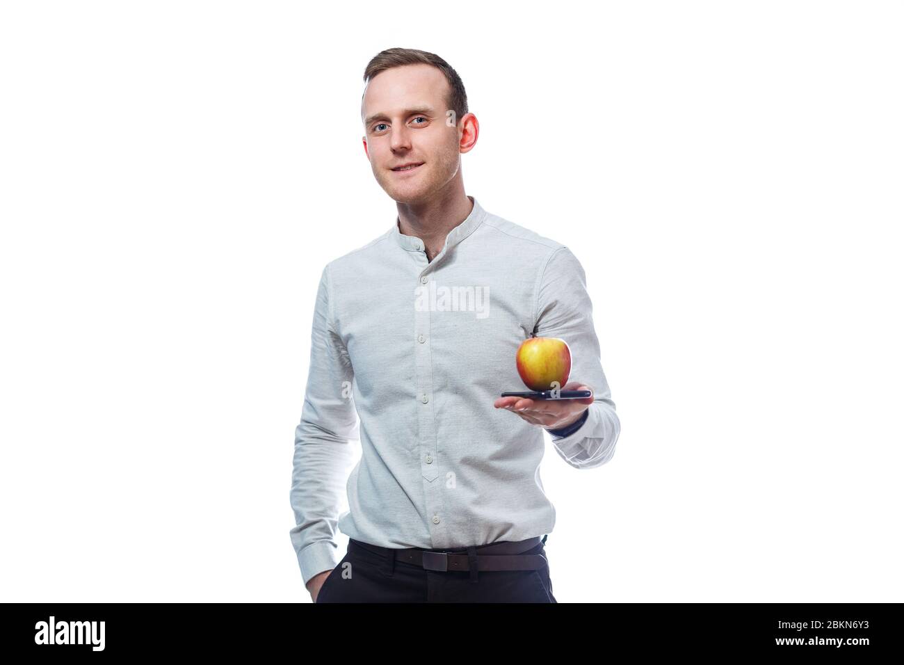 Caucasian male businessman holding a mobile phone in black and holding a red-yellow apple. He is wearing a shirt. Emotional portrait. Isolated on whit Stock Photo
