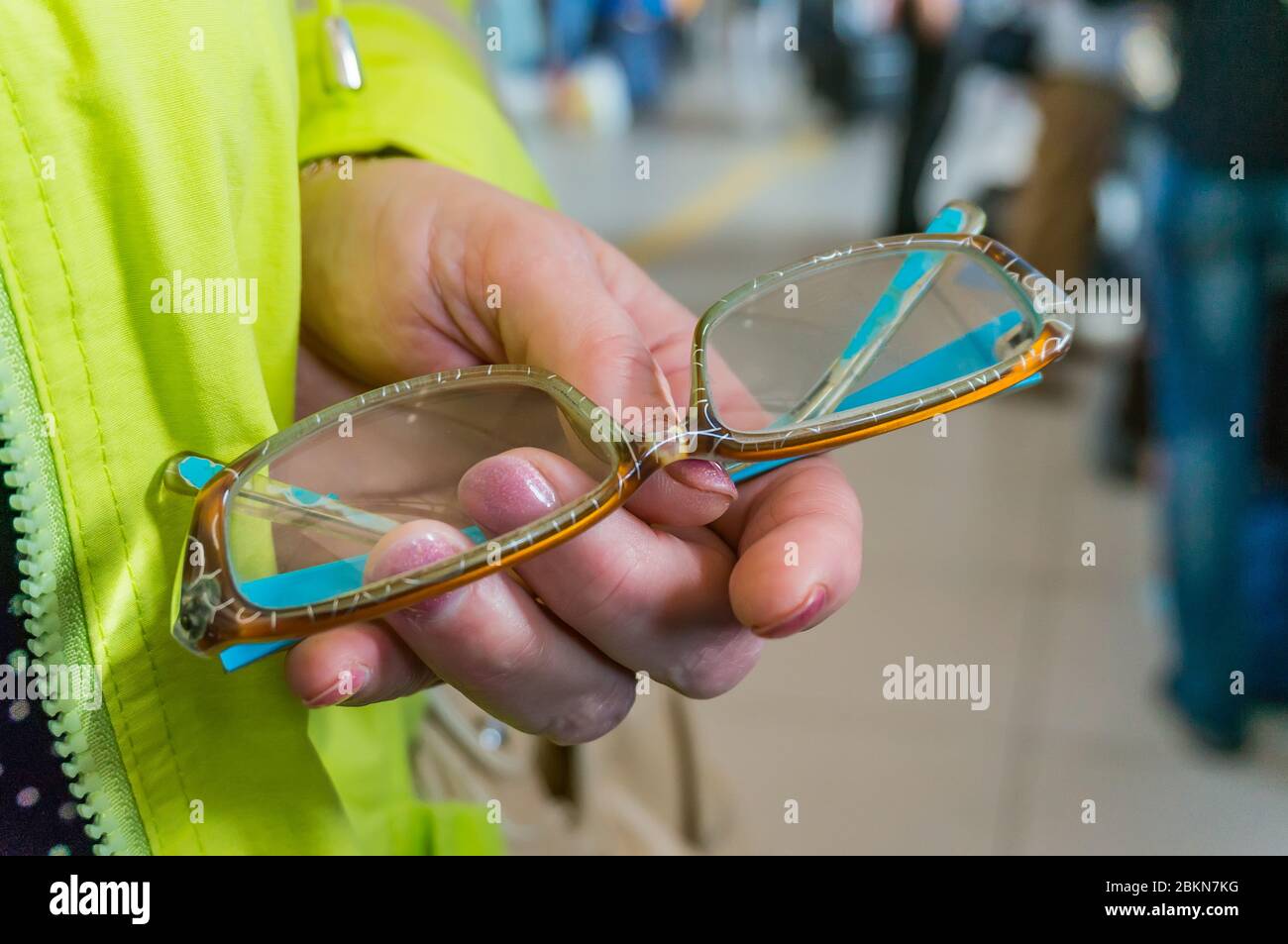 Reading glasses in a colored plastic frame in the hands of a woman. The concept of visual impairment with age Stock Photo