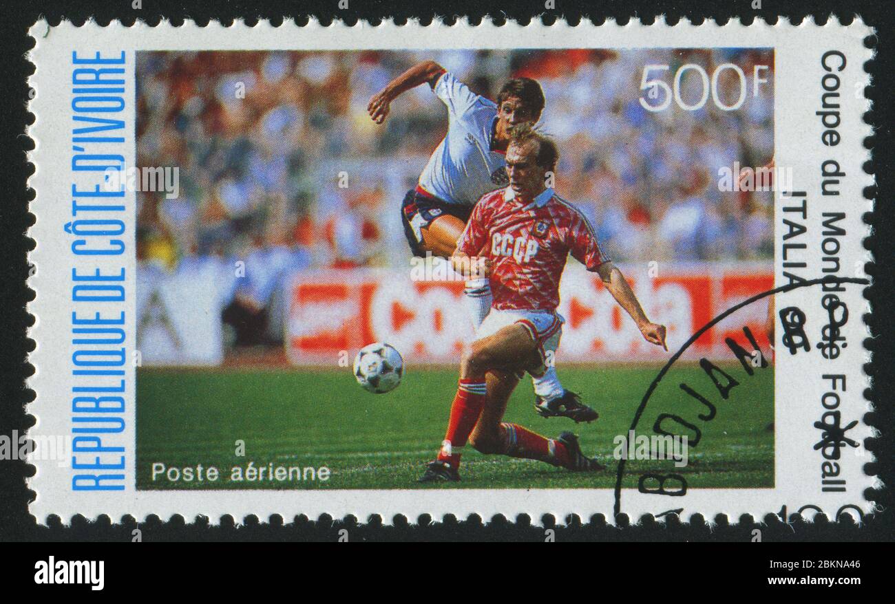 IVORY COAST - CIRCA 1990: stamp printed by Ivory Coast, shows Soccer players and ball, circa 1990. Stock Photo