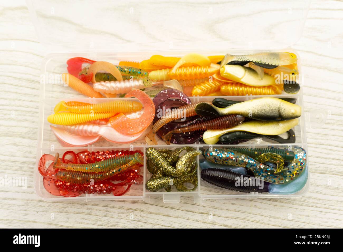 https://c8.alamy.com/comp/2BKNC6J/colorful-silicone-fishing-baits-with-plummets-on-wooden-table-toned-image-and-top-view-2BKNC6J.jpg