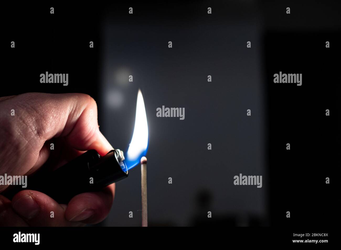 Lighting a match stick with a lighter isolated on a black background
