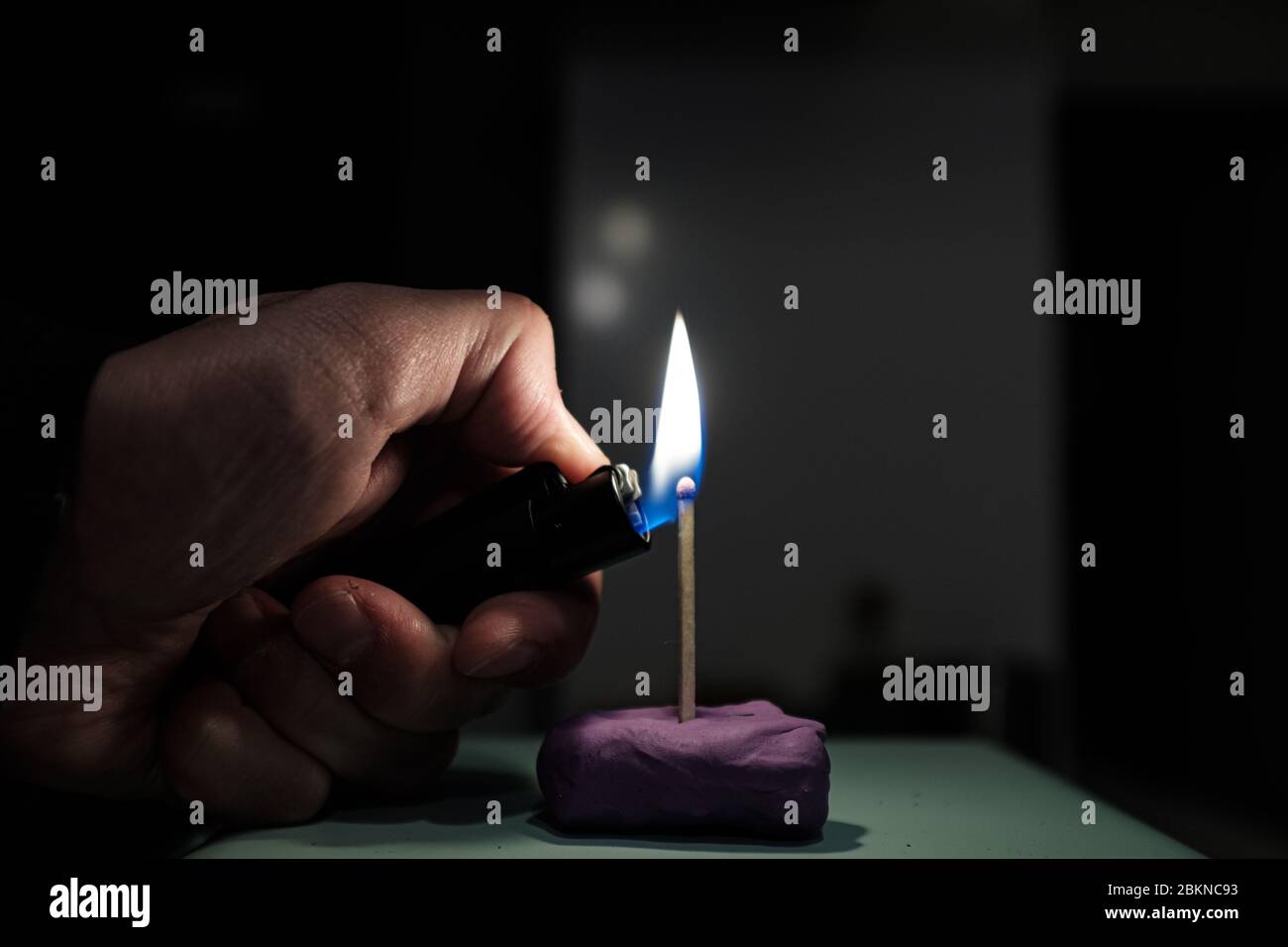 Lighting a match stick with a lighter isolated on a black background
