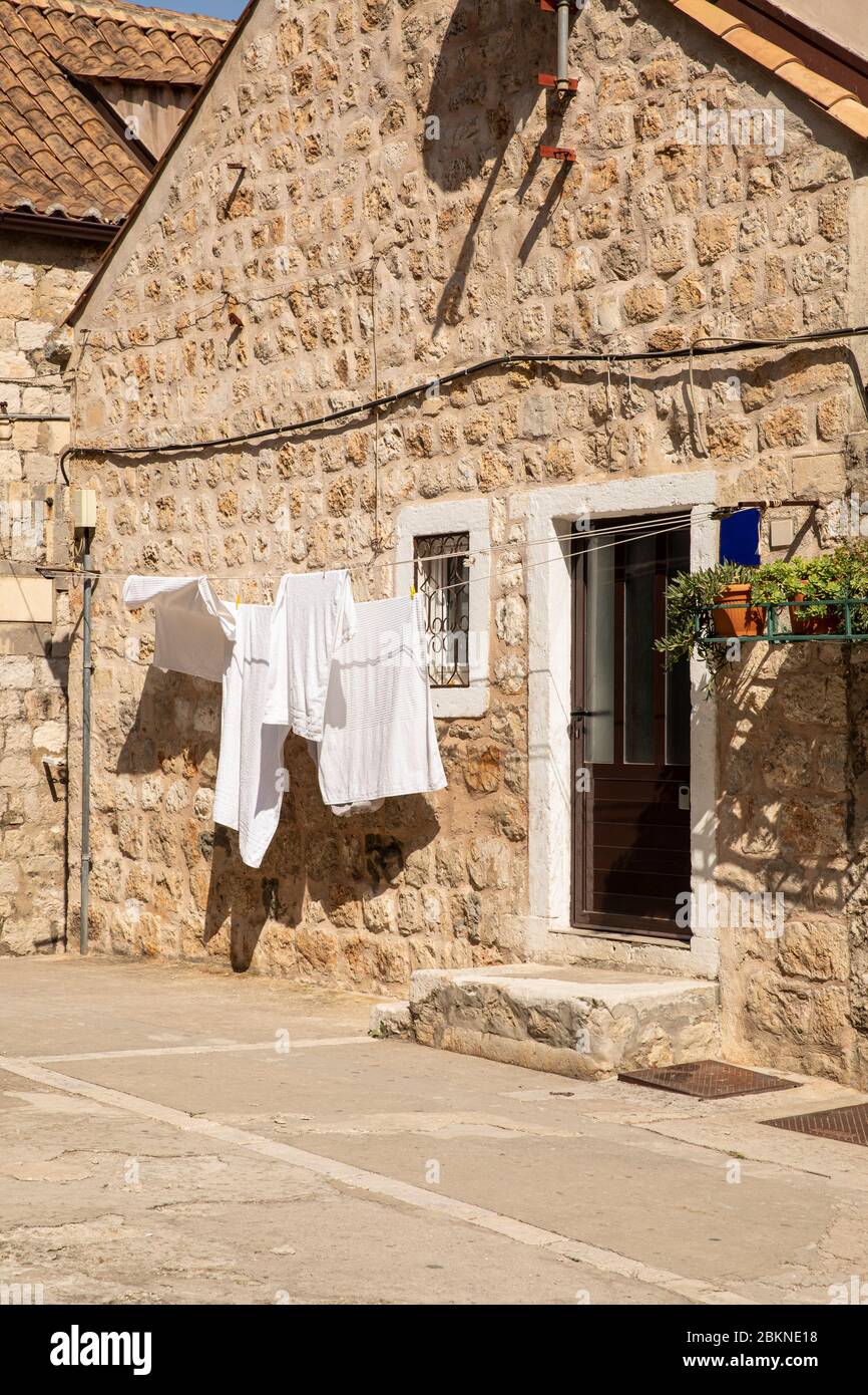 Fresh white laundry with towels hanging outside in front of a rustic old typical mediterranean house in the Old Town of Dubrovnik in Dalmatia, Croatia Stock Photo