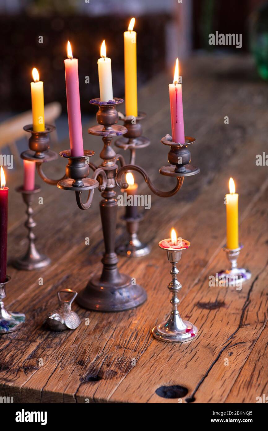 Different colored candles in a vintage metal candle holder burning to create a nice atmosphere in a house environmemt. An eclectic styled living with Stock Photo