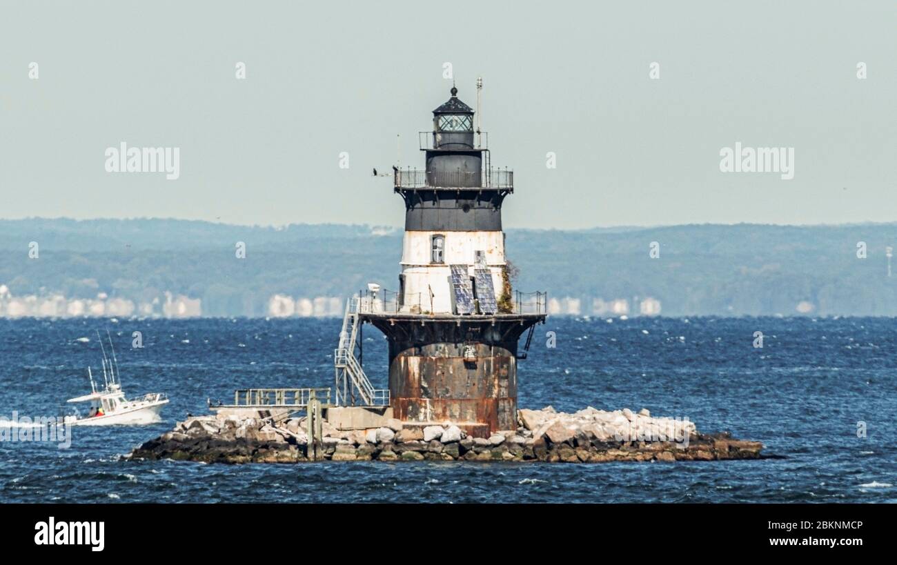 Orient Point lighthouse with Connecticut in the background a s personal fishing boat close in choppy water. Stock Photo
