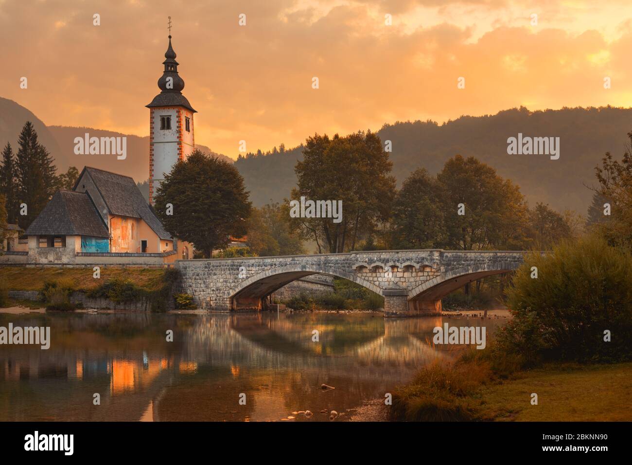 Church of St. John the Baptist and medieval stone bridge at lake Bohinj, Slovenia. Image is taken in early morning of august. Stock Photo