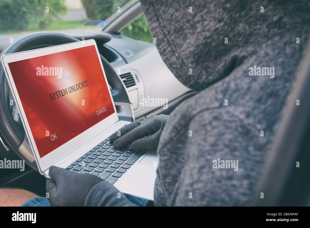 Hooded thief tries to break the car's security systems with laptop