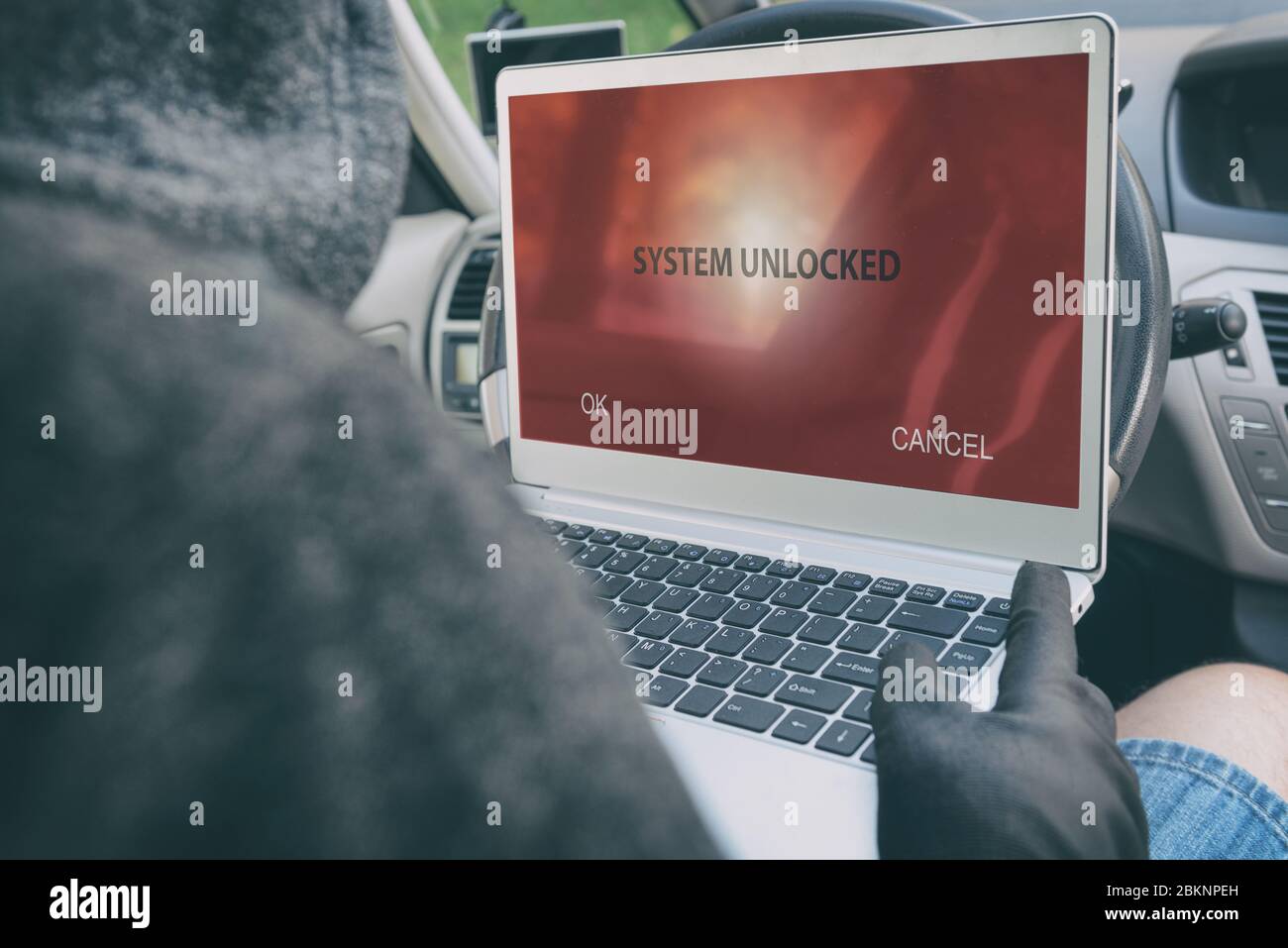 Hooded thief tries to break the car's security systems with laptop