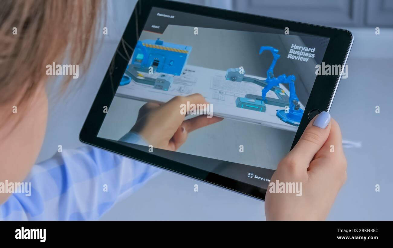 MOSCOW, RUSSIA - AUGUST 1, 2019. Woman using tablet with augmented reality app - virtual model of conveyor line. Future, AR, production, industrial Stock Photo