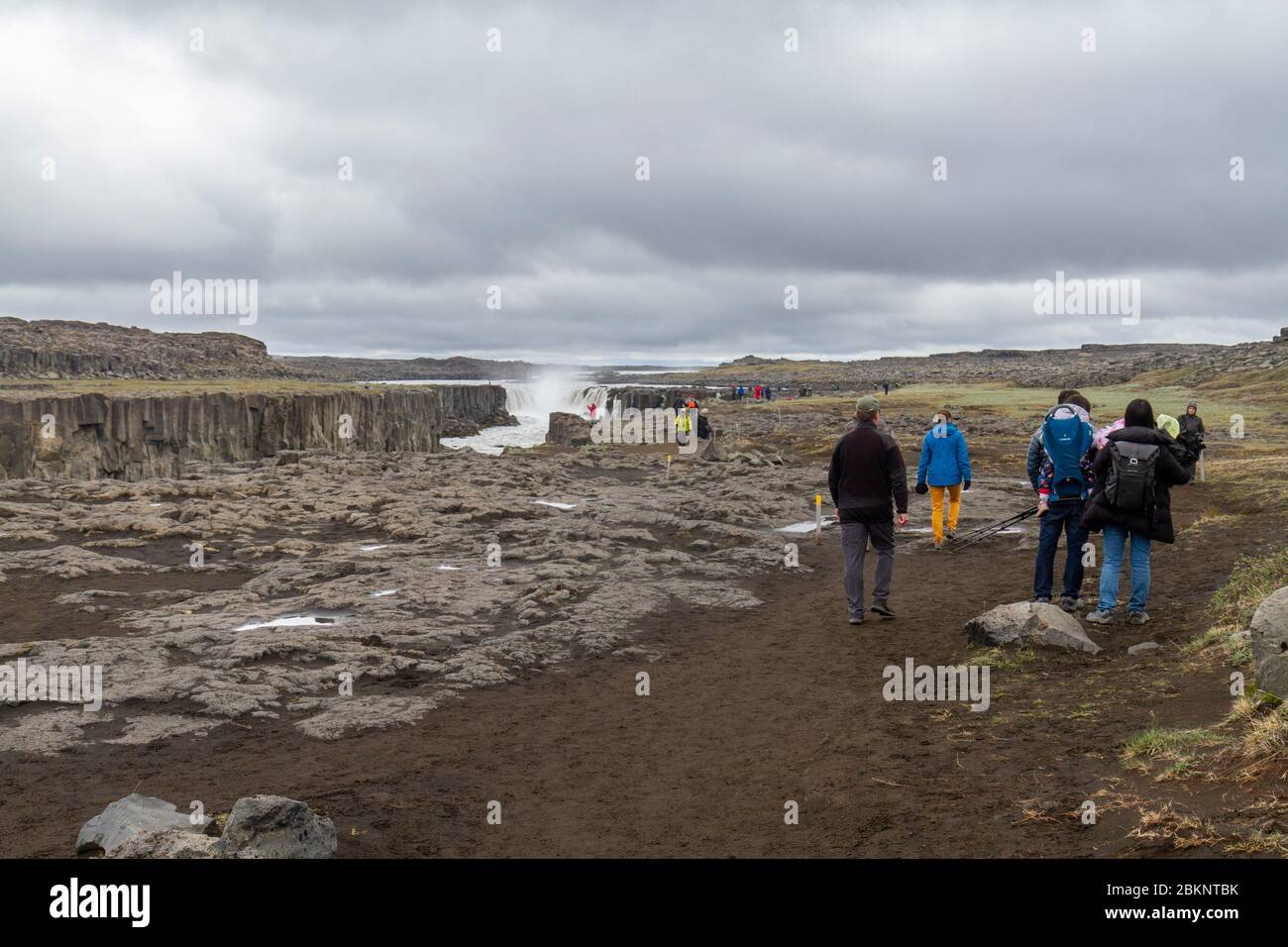 Visitors walking towards the Selfoss waterfall in the Jökulsárgljúfur canyon upriver from the more famous Dettifoss waterfall, northern Iceland. Stock Photo