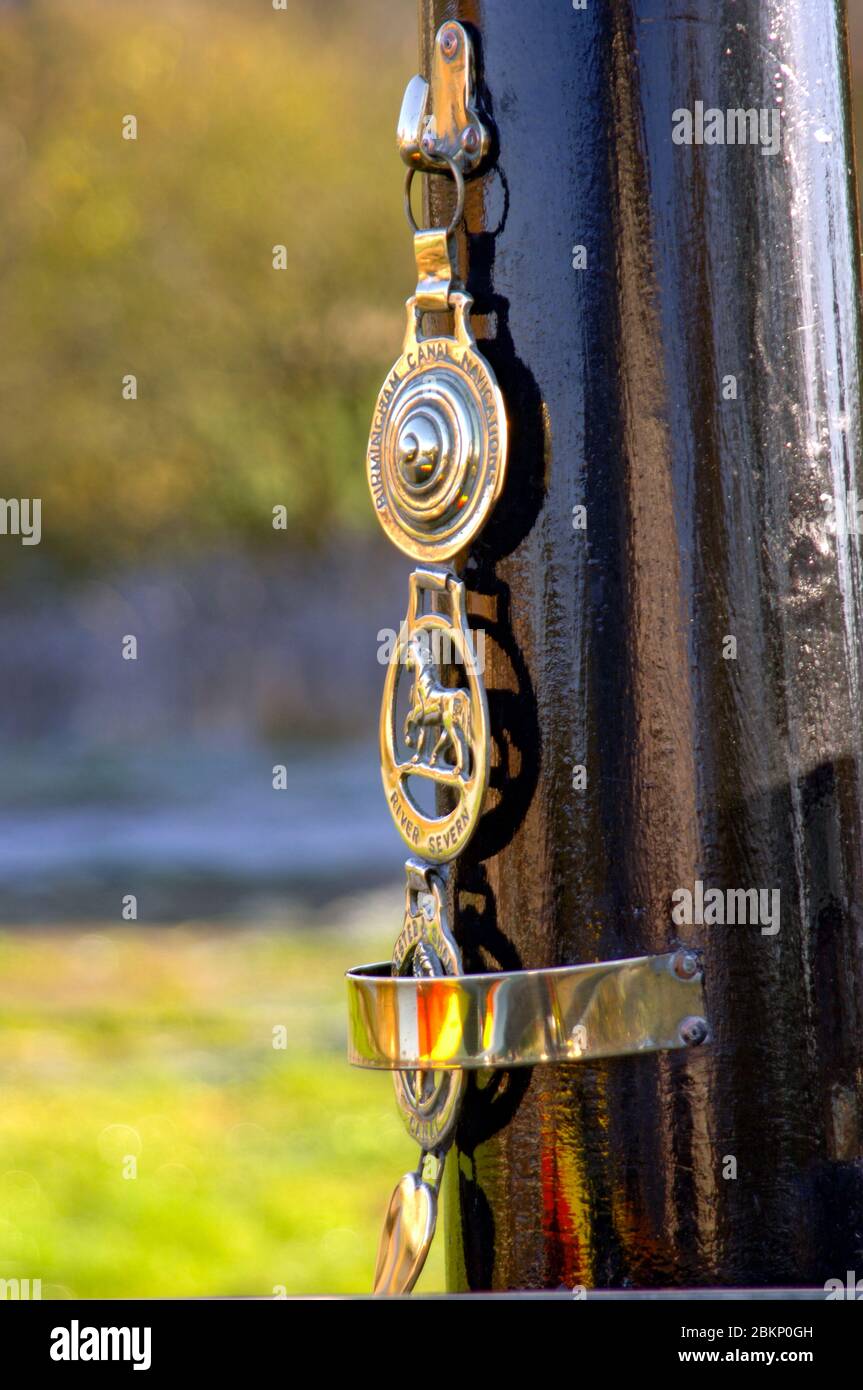 Horse brasses decorate a shiney black-painted chimney on a canal boat. Stock Photo