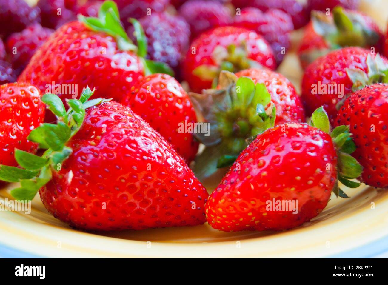 Plate with summer ripe berries - strawberries, strawberries, raspberries. Vitamin delicious simple natural vegan juicy dessert. The aromas of summer. Berries in warm sunlight. Stock Photo
