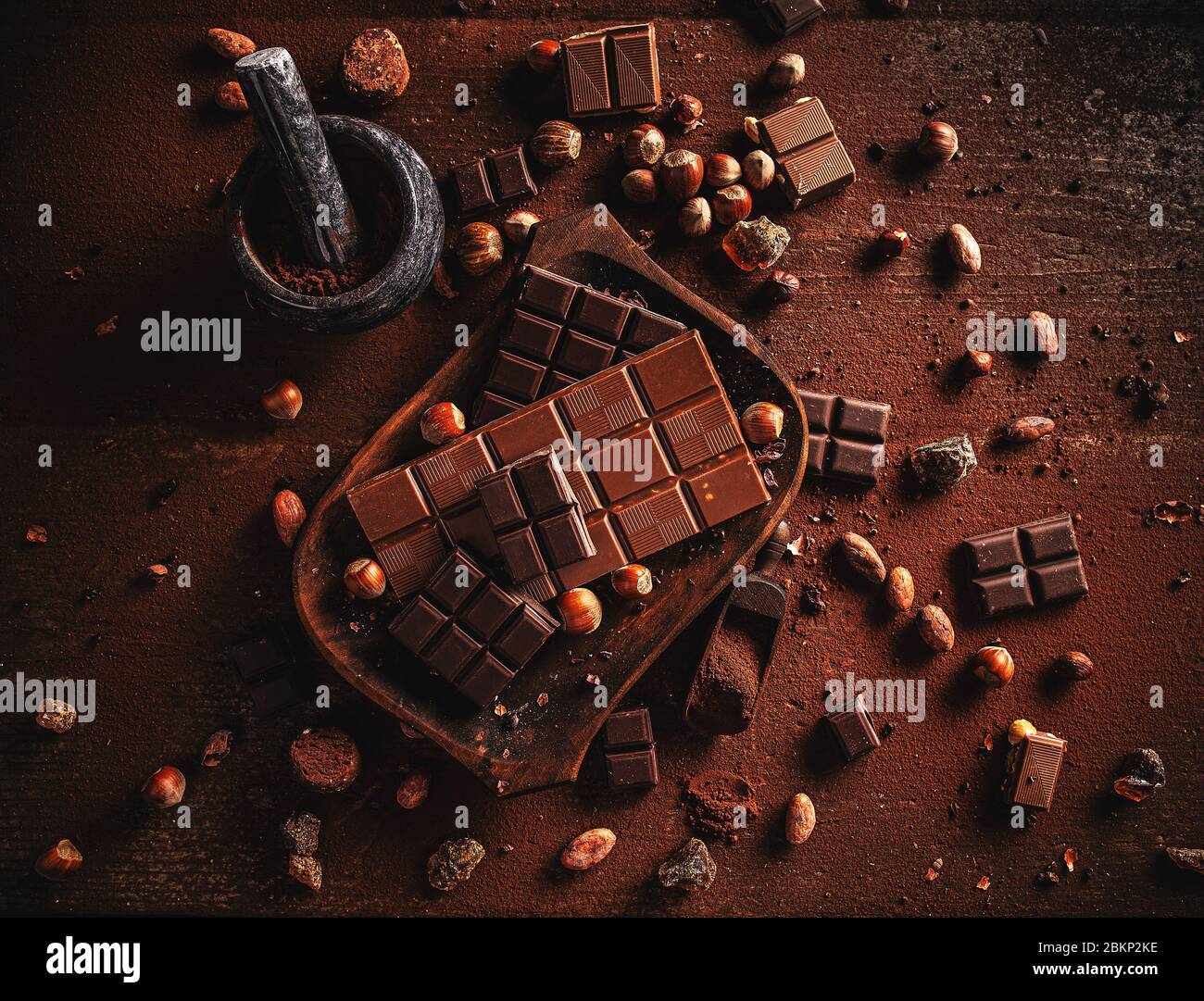 Cocoa powder, beans and chocolate bar pieces on dark wooden background. Stock Photo