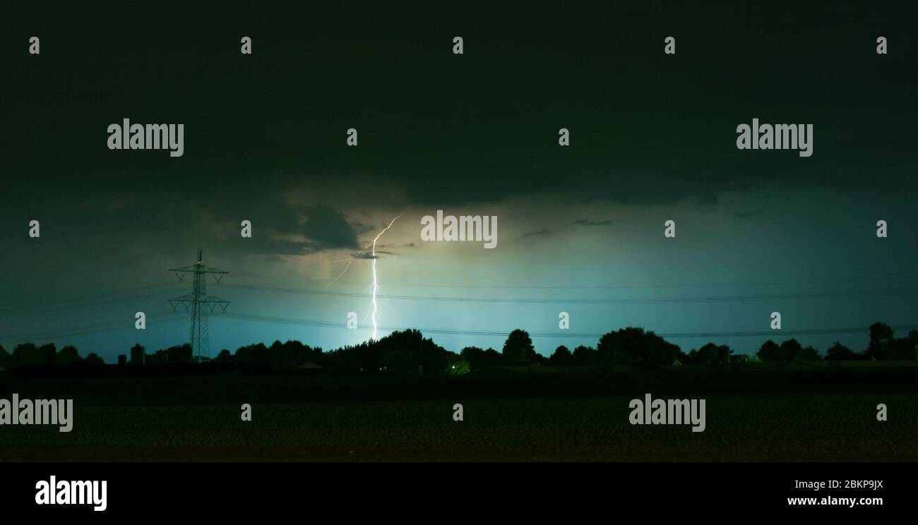 Lightning bolt strikes behind highvoltage pylon with power lines Stock Photo Alamy