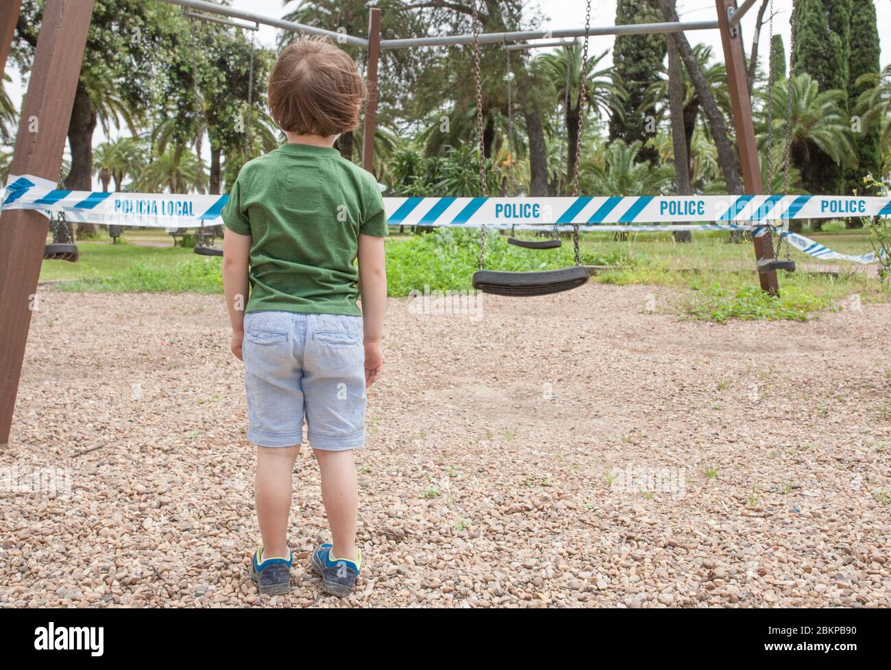 Litle boy standing front playgrounds taped off. Covid-19 government restrictions on public life Stock Photo
