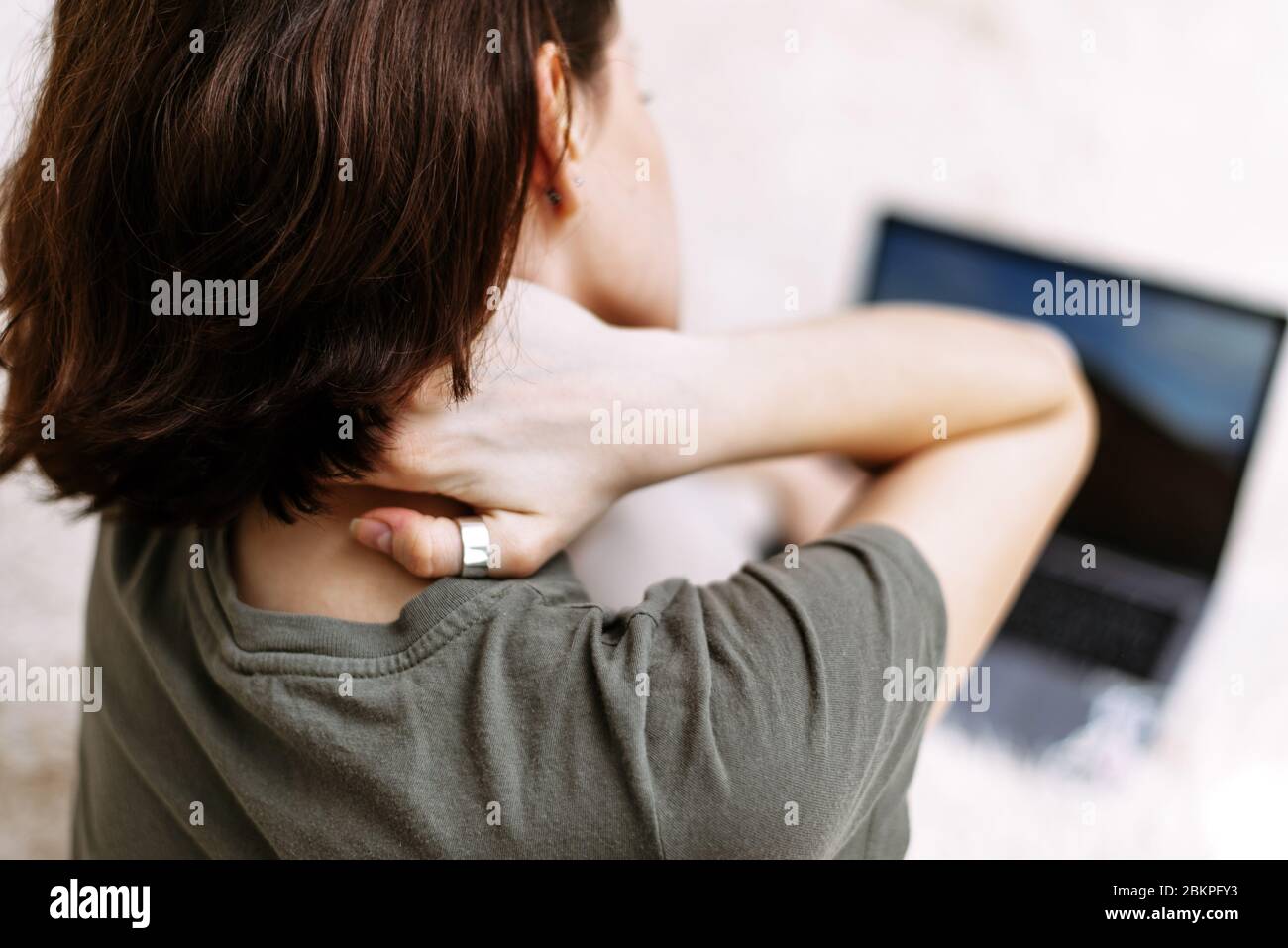 Tired woman massaging rubbing stiff sore neck tensed muscles fatigued from computer work in incorrect posture feeling hurt joint shoulder back pain ache, fibromyalgia concept, close up rear view. Stock Photo