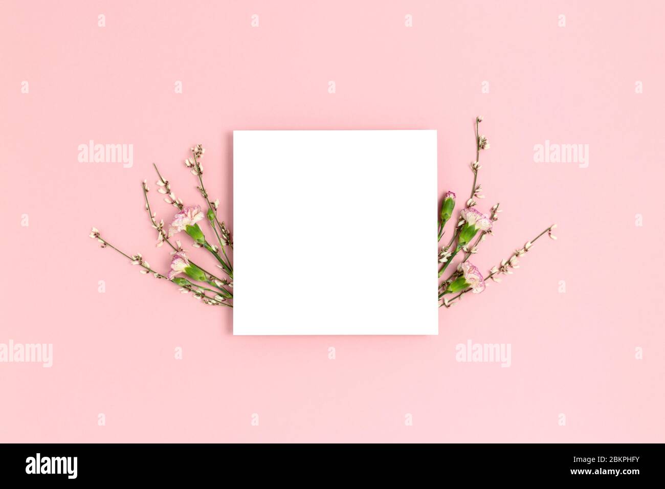 Frame made of flowers on a pink pastel background. Paper card mockup ...