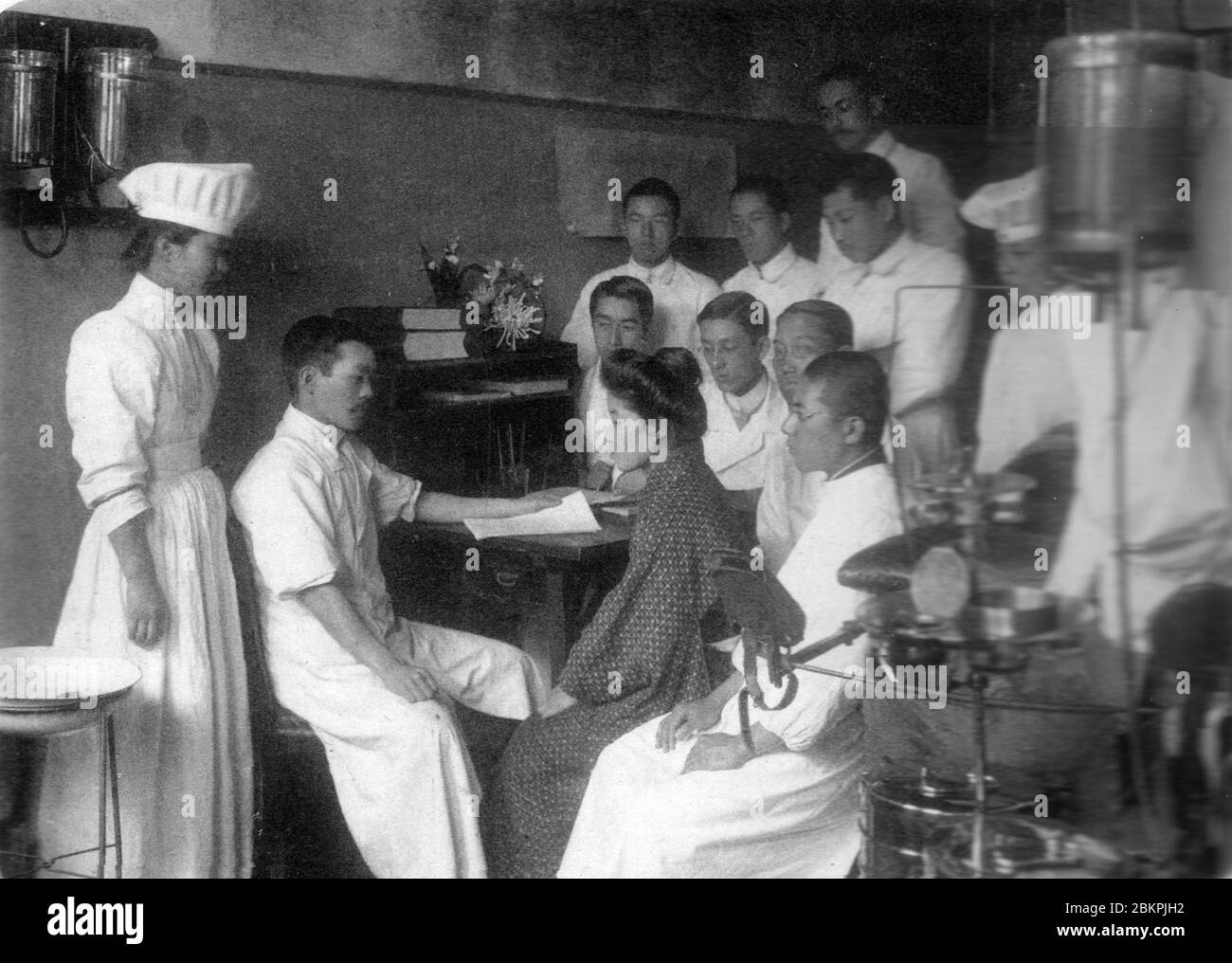[ 1910s Japan - Japanese Doctor and Patient ] —   Doctors-to-be and nurses attend to a patient at Okayama Iigakku Senmon Gakko, a medical school in Okayama, in 1910 (Meiji 34).  20th century vintage gelatin silver print. Stock Photo