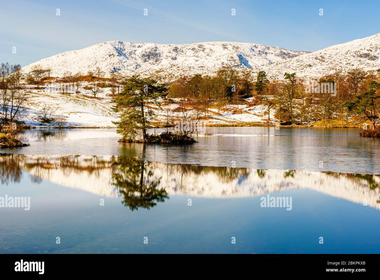 Partly-frozen Tarn Hows with Coniston Old Man and Brim Fell behind, Lake District Stock Photo