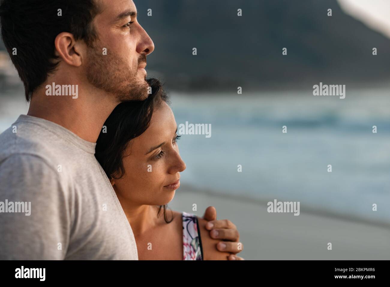 Young couple looking out at the ocean at sunset Stock Photo