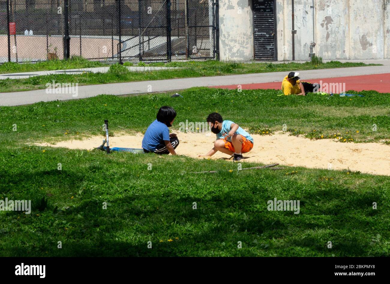 two boys play in a sandbox with face masks on in Van Cortlandt Park, an example of the impact on children of the coronavirus or covid-19 pandemic Stock Photo