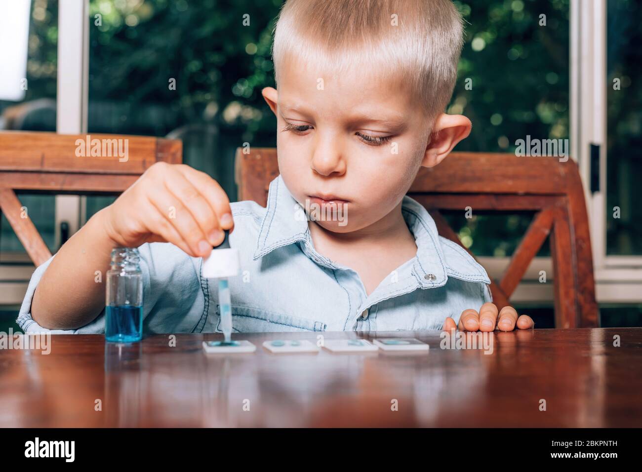 Little boy doing the experimental laboratory activity with colored