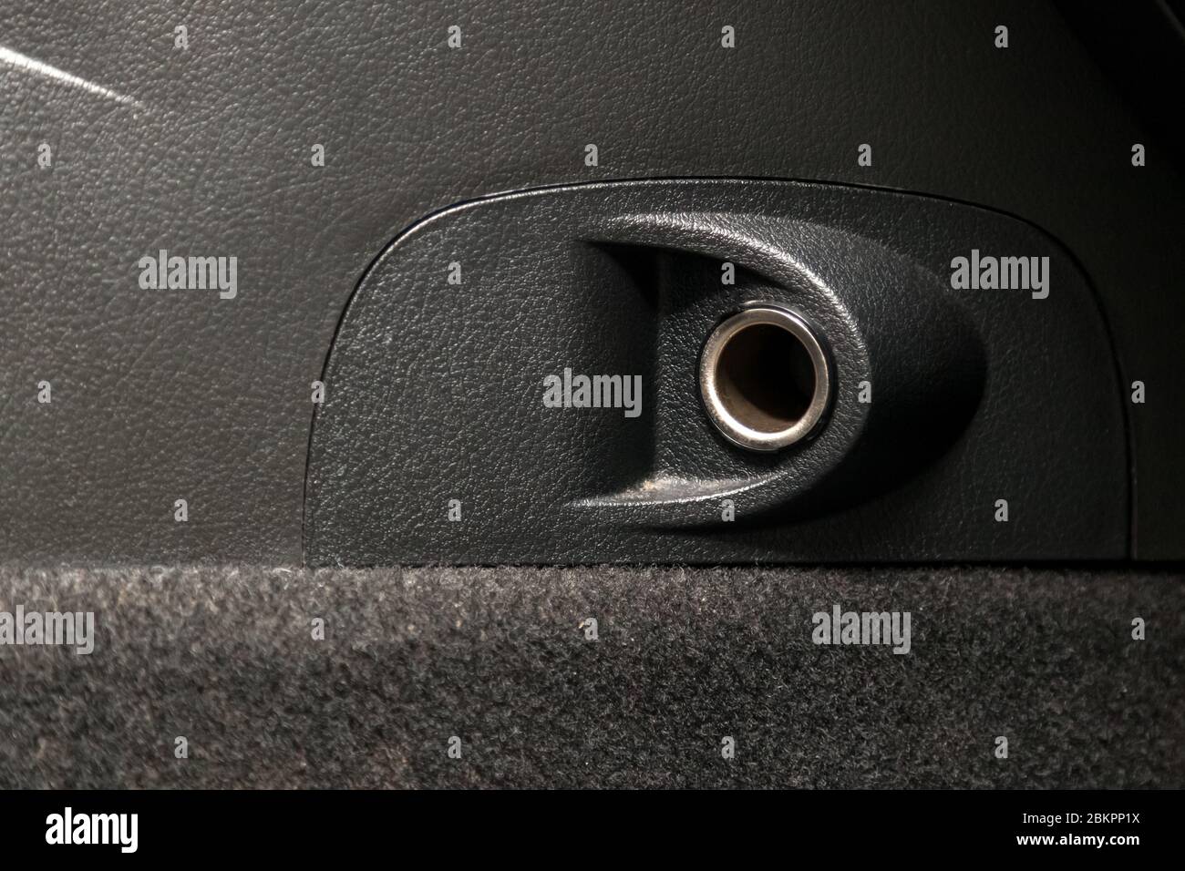 Empty cigarette lighter socket in a car on a black plastic panel. Stock Photo