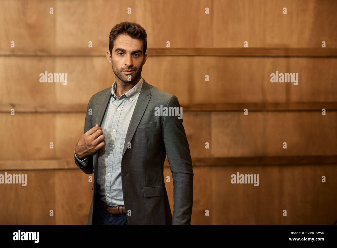 Confident man in a blazer standing in a trendy lounge Stock Photo
